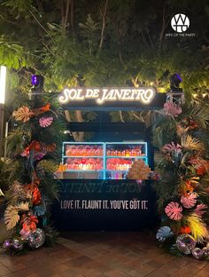 the entrance to sol de janero is decorated with tropical foliage and neon lights at night