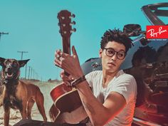 a man with glasses holding a guitar next to a dog