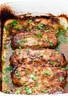 three pork chops in a baking dish with parsley