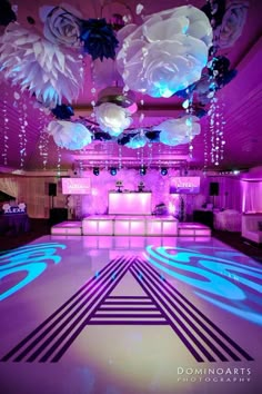 the dance floor is lit up with blue and purple lights, flowers and chandeliers