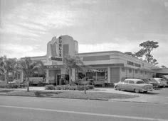 an old black and white photo of a building with cars parked in front of it