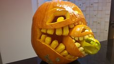 a pumpkin carved to look like a monster's head with teeth and fangs on it