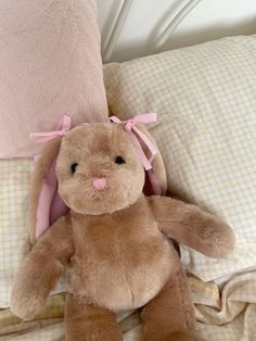 a brown stuffed animal sitting on top of a bed next to pillows and pillow cases