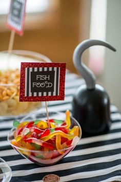 there is a bowl of gummy bears on the table with a sign that says fish food