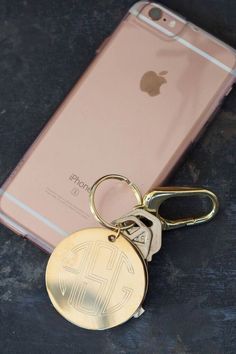 a gold keychain is sitting next to an iphone with the initials on it