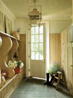 an entry way with flowers and pots on the shelf next to the door is shown