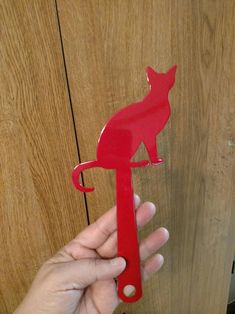 a person holding a red paper cut out of a cat on a keychain