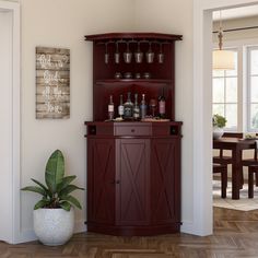 a wooden cabinet with wine glasses on it in a living room next to a potted plant