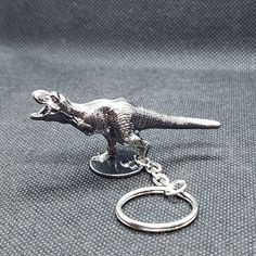 a metal keychain with a small toy dinosaur on it