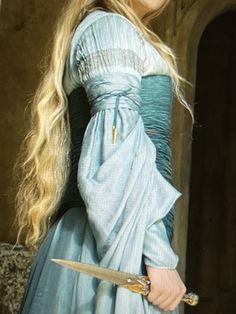 a woman with long blonde hair wearing a blue dress and holding a knife in her hand