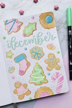 an open notebook with christmas cookies on it and a marker pen next to the book