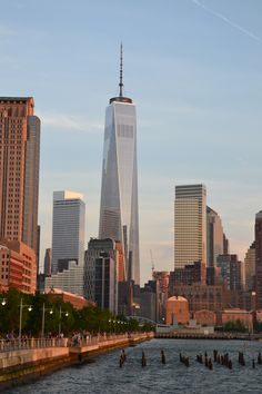 the skyline of new york city with skyscrapers and boats in the water at sunset