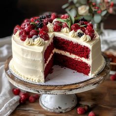 a red velvet cake with white frosting and fresh berries on top is cut in half