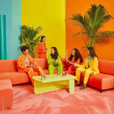 four women sitting on couches in brightly colored room with palm tree and potted plant