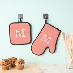 two oven mitts hanging on the wall with muffins in front of them