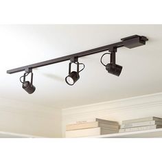 three spotlights are hanging from the ceiling in a room with white walls and bookshelves