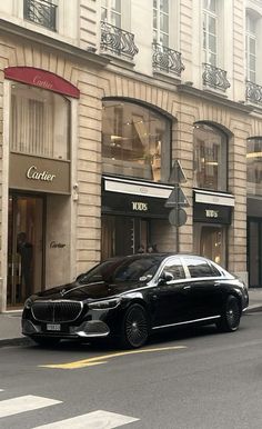 a black car is parked on the side of the road in front of a building