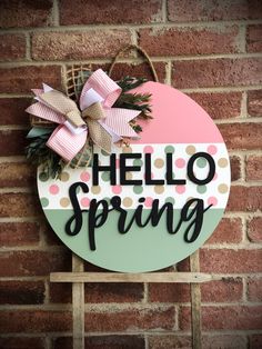 a sign that says hello spring hanging on a brick wall