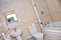 a white toilet sitting next to a bath tub in a bathroom on top of tile flooring