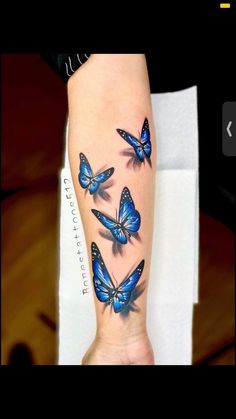 a woman's leg with three blue butterflies on her left arm and the bottom half of