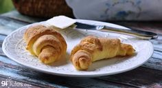 two croissants on a white plate next to a fork