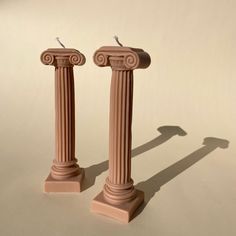 two pink pedestals are standing next to each other on a white surface and one is casting a shadow