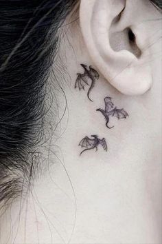 a woman's behind the ear with three small dragon tattoos on her left side