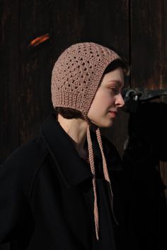 a woman wearing a crocheted hat and scarf with a camera in front of her