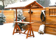 a wooden gazebo in the snow next to a fence