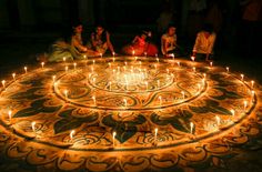 several people sitting around a lit candle in the shape of a circle