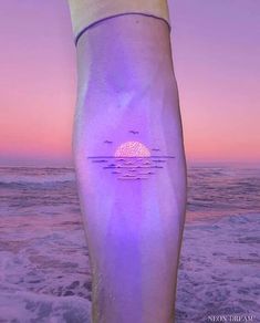 a person standing on the beach at sunset with their foot in the air and an ocean view behind them