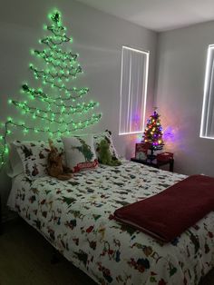 a christmas tree is lit up in the corner of a room with a bed and window