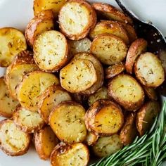 a white plate topped with sliced potatoes and rosemary garnish next to a fork