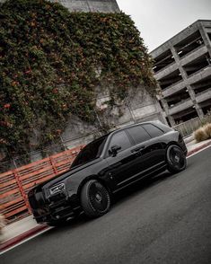 a black car parked on the side of a road next to a tall planter