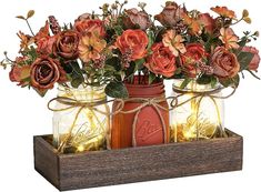 two mason jars with flowers in them are sitting on a wooden box that has string lights attached to it