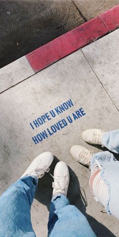 two people standing next to each other on a sidewalk with words painted on the ground