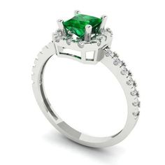 an emerald and diamond engagement ring on a white background with the center stone surrounded by small diamonds