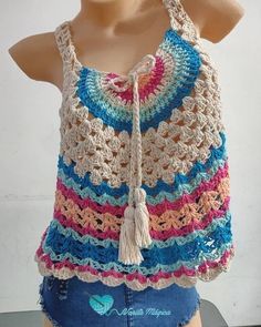 a mannequin wearing a multicolored crocheted top with tassels