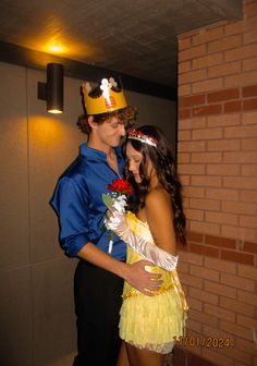 a man and woman dressed in costumes standing next to each other near a brick wall