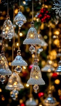 christmas bells hanging from a tree with lights in the background and snowflakes on it