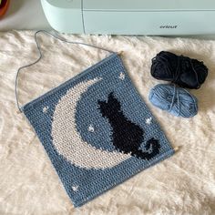 a crocheted rug with a cat on it next to some yarn and a machine