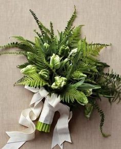 a bouquet of flowers and greenery is tied to a beige wall with white ribbon