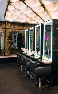 a dining room with black chairs and tables in front of a mirrored wall that has lights on it