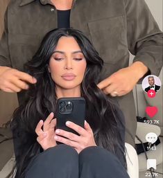 the woman is getting her hair styled by someone else in front of her cell phone