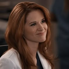 a woman with red hair is smiling at the camera while wearing a white shirt and black tie