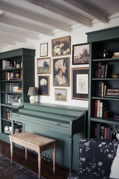 a living room with bookshelves and pictures on the wall, along with a bench