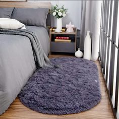 a bed room with a neatly made bed and a purple rug