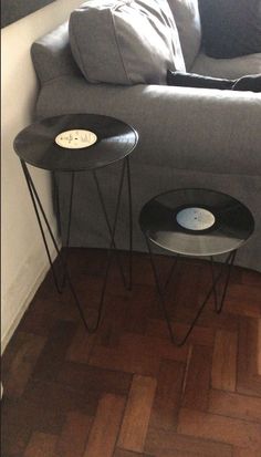 two black tables sitting on top of a wooden floor next to a gray sectional couch