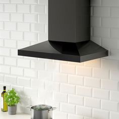 a black stove top oven sitting next to a pot on a kitchen counter with white tiles