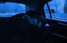 two people sitting in the back seat of a car, one is covering his face